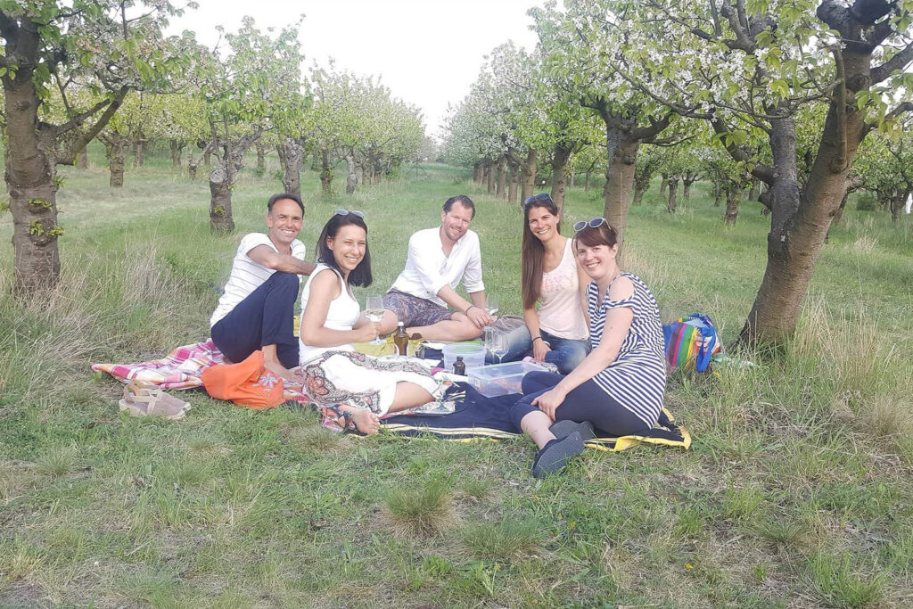 Gruppe von Menschen macht Picknick im Kirschgarten